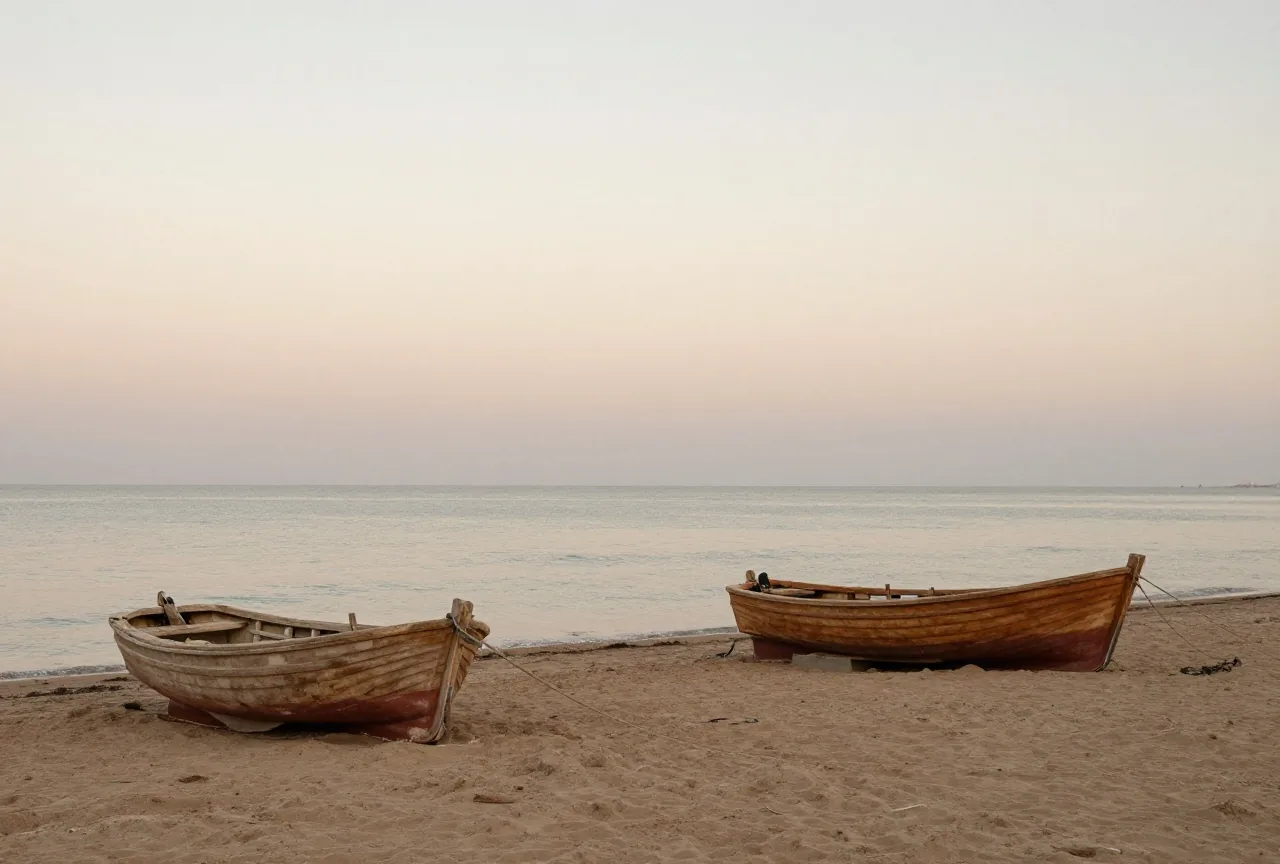 Ein sandiger Mittelmeerstrand in der Abenddämmerung mit kleinen hölzernen Fischerbooten auf dem Sand