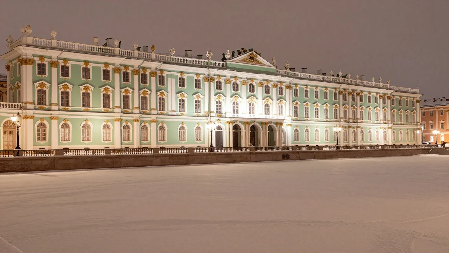 Eine lange Palastfassade in Hellgrün und Weiß an einem zugefrorenen Fluss bei Nacht mit Laternen und Schnee