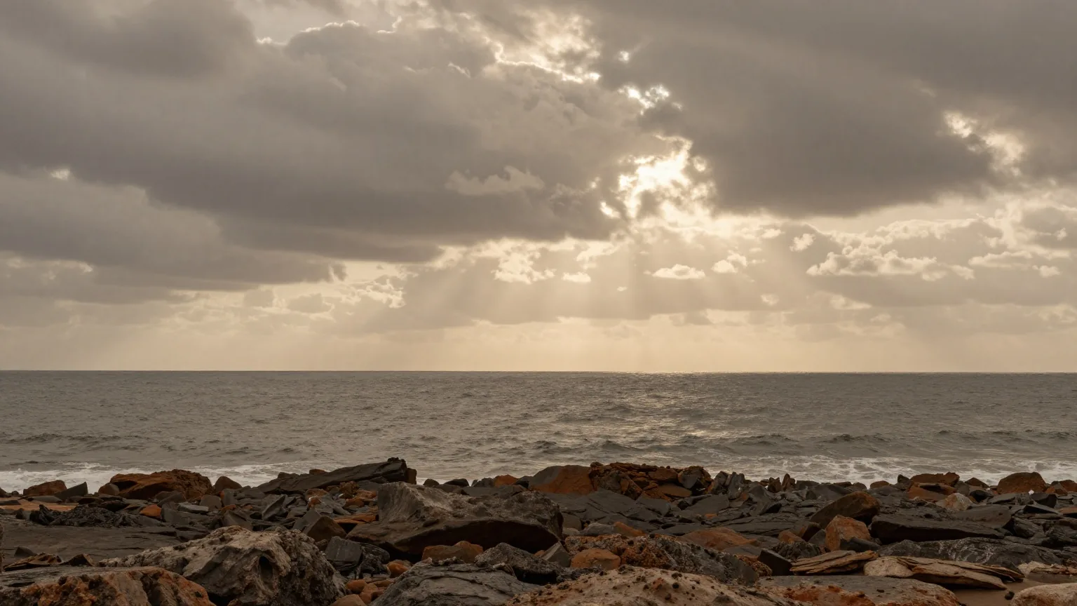 Der offene Atlantik in der Abenddämmerung von einer felsigen westafrikanischen Küste aus, dunkle Wolken über dem Horizont
