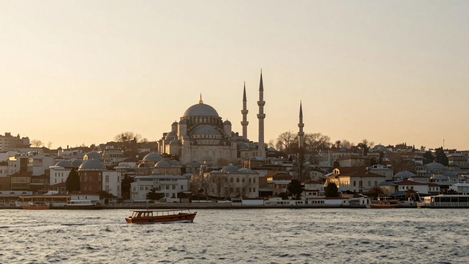 Blick über den Bosporus bei Sonnenaufgang auf eine Silhouette aus Kuppeln und schlanken Minaretten mit kleinen Holzbooten