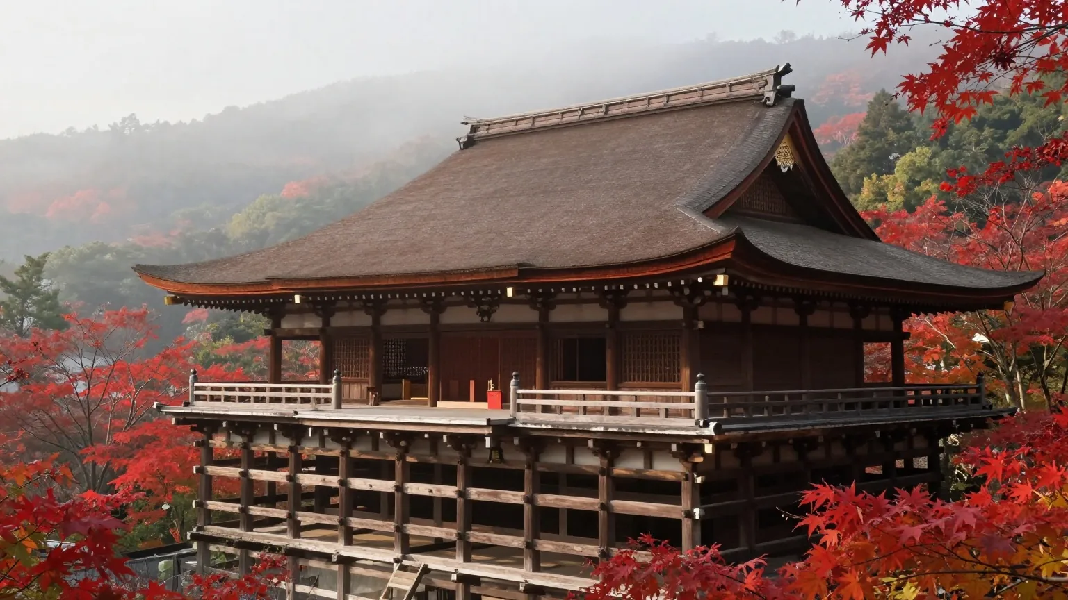 Eine japanische Tempelhalle aus Holz mit geschwungenen Dächern an einem bewaldeten Hang mit rotem Herbstlaub im Nebel